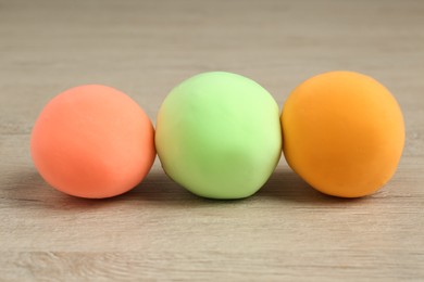 Different color play dough on wooden table, closeup