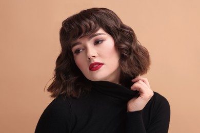 Portrait of beautiful young woman with wavy hairstyle on beige background