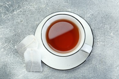 Aromatic tea in cup and teabags on grey table, top view