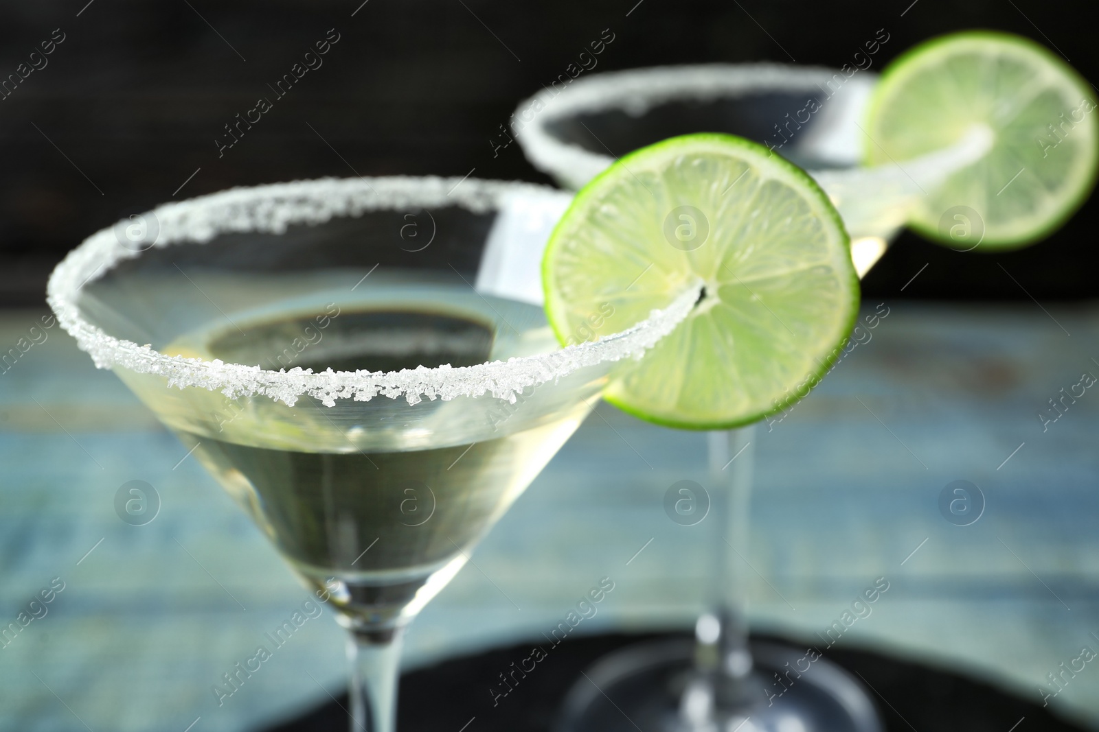 Photo of Glasses of Lime Drop Martini cocktail on table, closeup