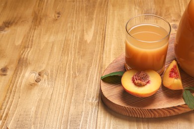 Delicious peach juice, fresh fruit and leaves on wooden table. Space for text