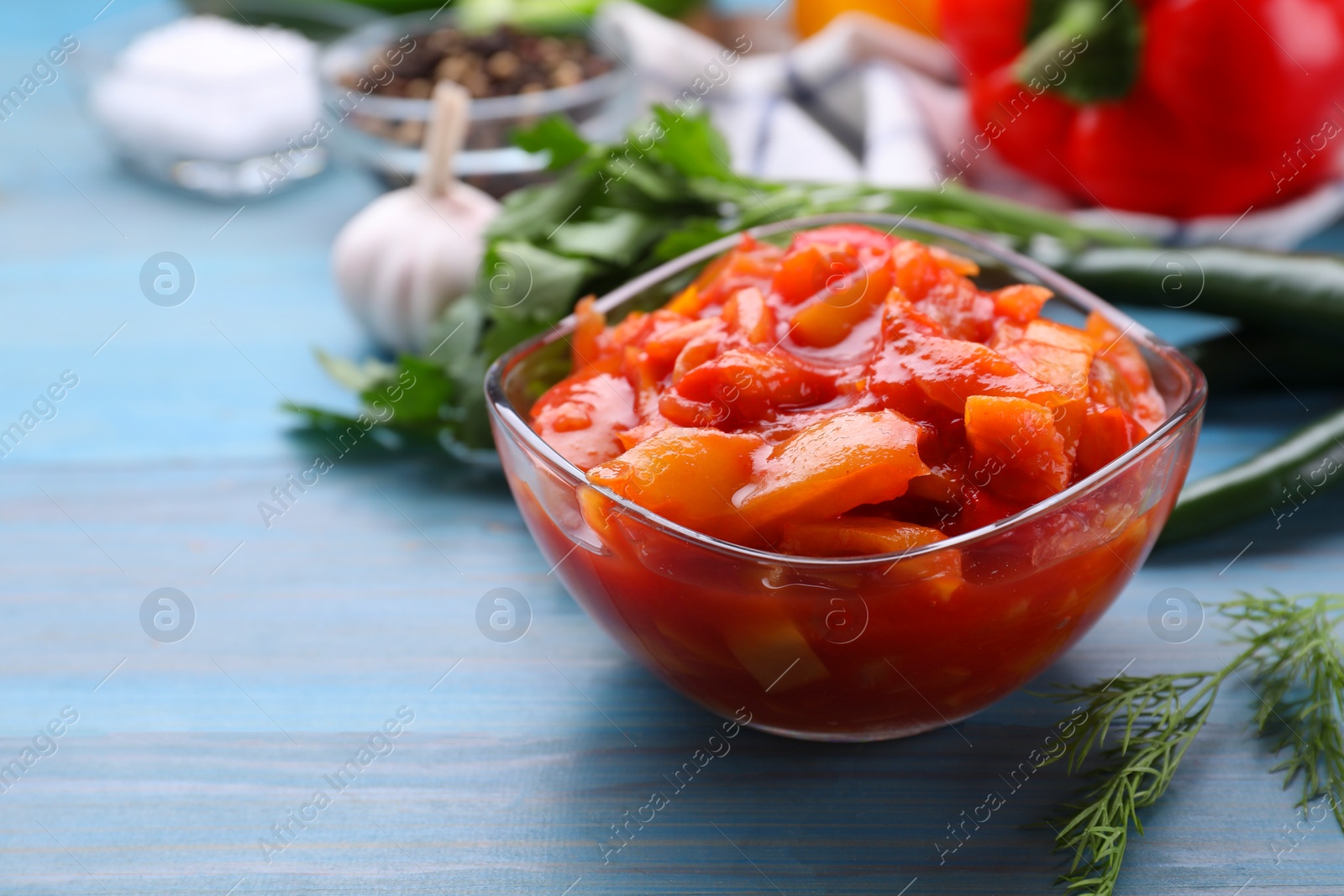 Photo of Bowl of delicious lecho on light blue wooden table, closeup. Space for text