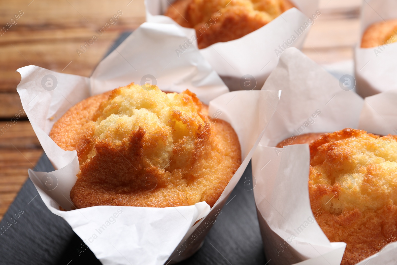 Photo of Delicious sweet muffins on wooden table, closeup