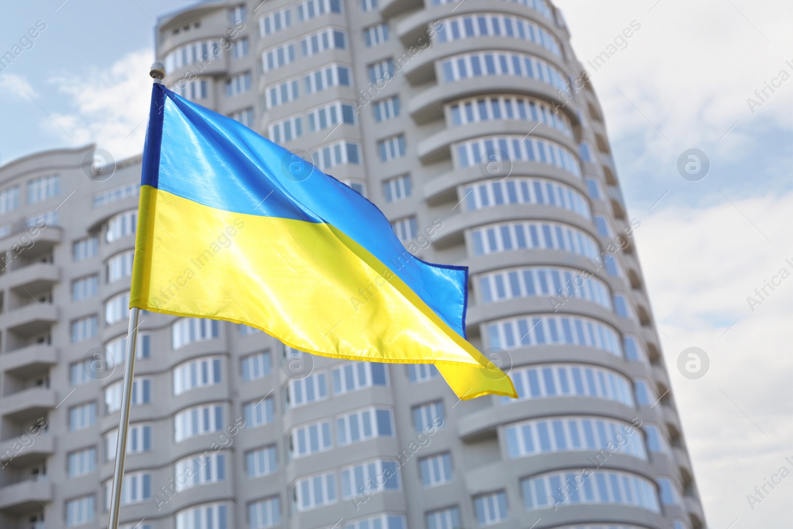 Photo of National flag of Ukraine fluttering near building on sunny day