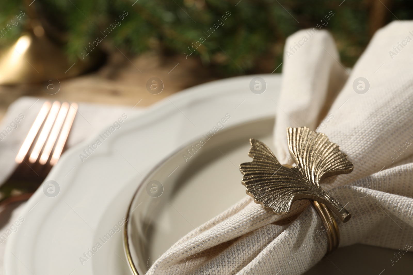 Photo of White fabric napkin with beautiful decorative ring for table setting on plate, closeup