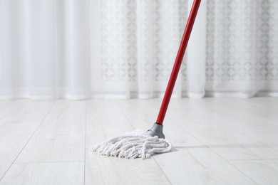 Photo of Cleaning dirty wooden floor with mop indoors