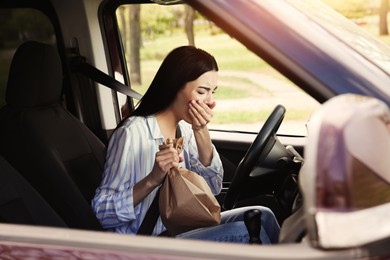 Photo of Young woman with paper bag suffering from nausea in car