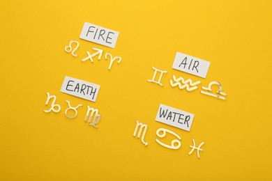 Photo of Zodiac triplicity. Four elements and corresponding signs on yellow background, flat lay