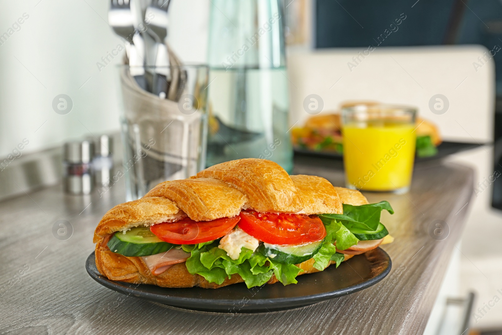 Photo of Tasty croissant sandwich with sausage on table