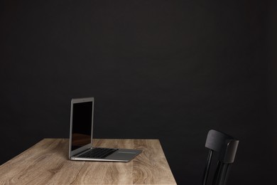 Photo of New modern laptop on empty wooden table indoors, space for text