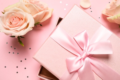 Photo of Elegant gift box, beautiful flowers and confetti on pink background, flat lay