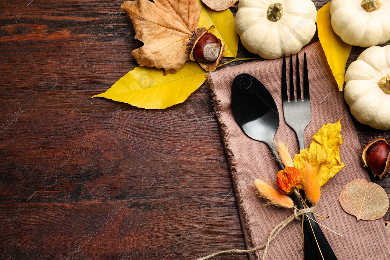 Photo of Seasonal table setting, space for text. Cutlery with pumpkins and autumn leaves on wooden background, flat lay