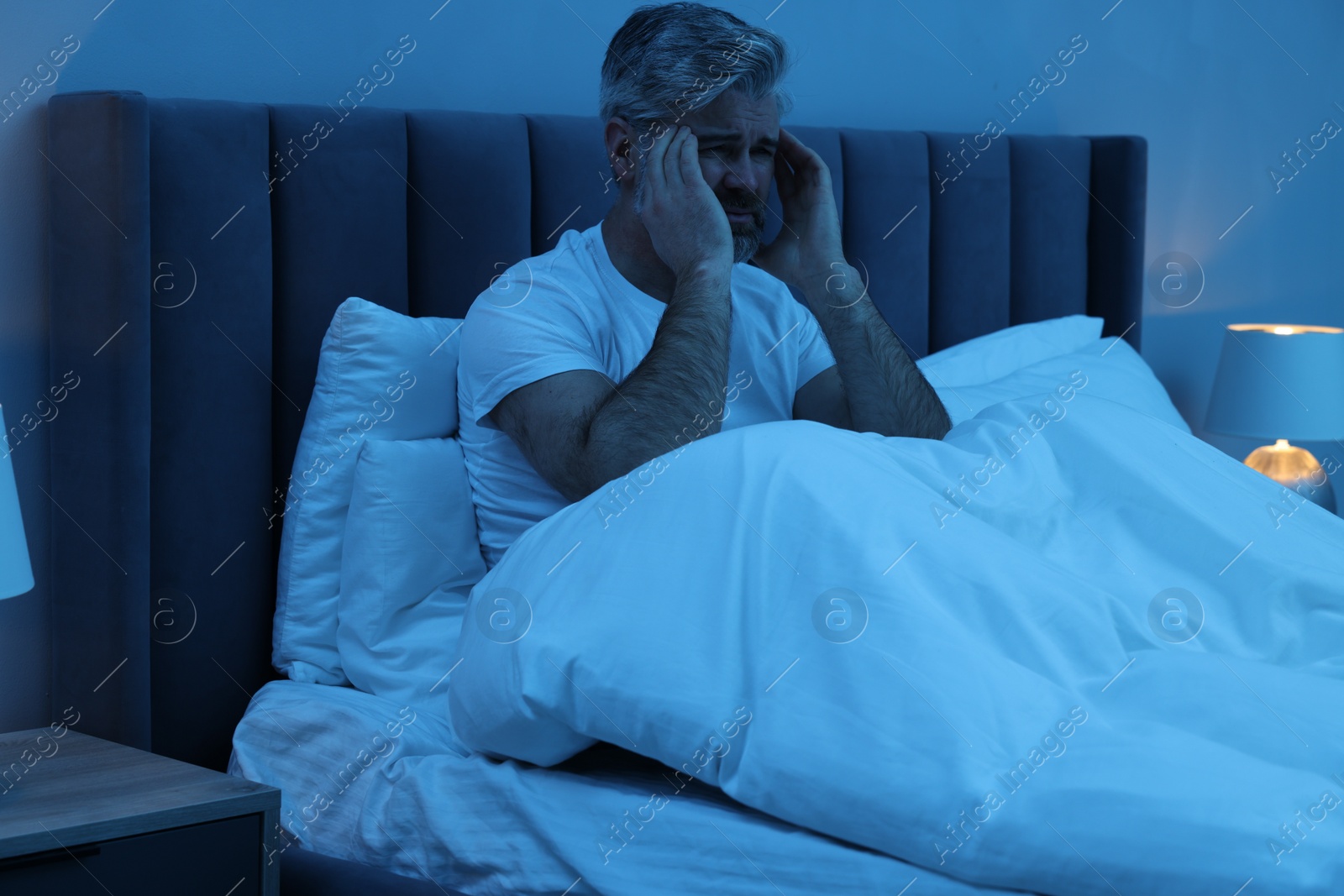 Photo of Mature man suffering from headache in bed at night