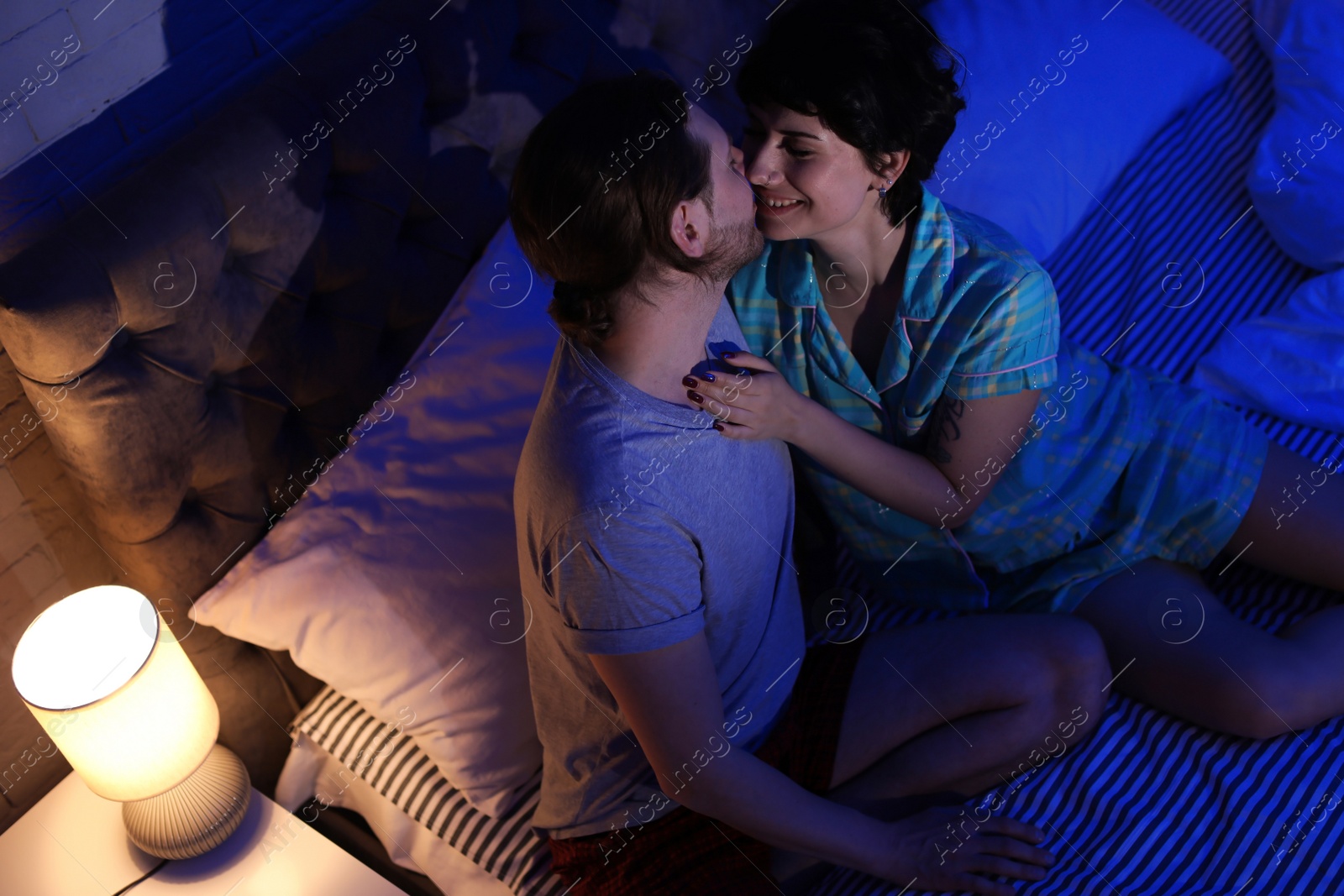 Photo of Young couple in love on bed at night time