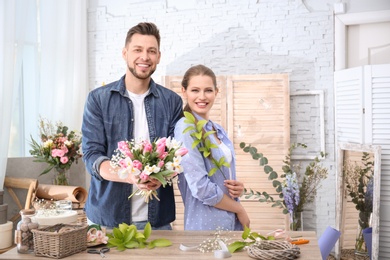 Photo of Decorators with beautiful flowers at workplace