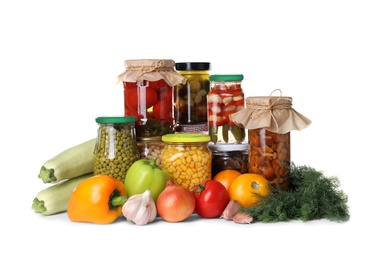 Photo of Fresh vegetables and jars of pickled products on white background