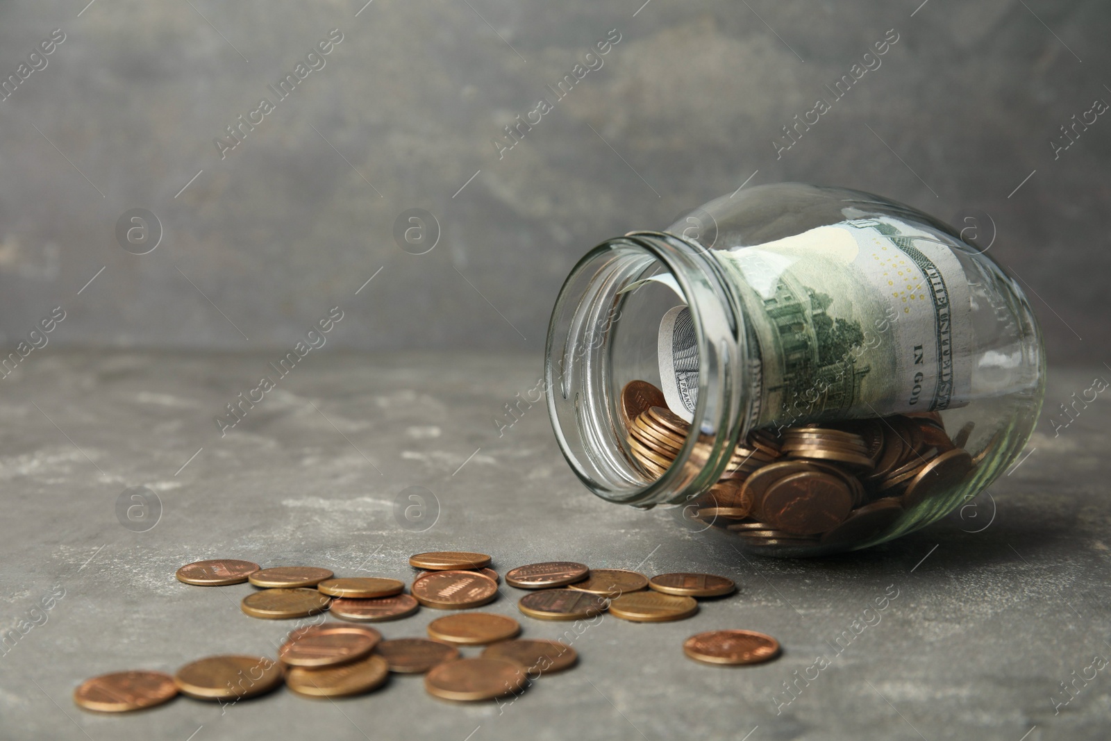 Photo of Overturned glass jar with money on grey stone table