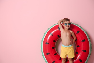 Cute little boy with inflatable ring on color background