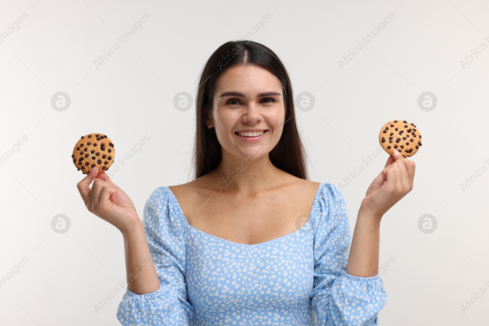 Photo of Young woman with chocolate chip cookies on white background