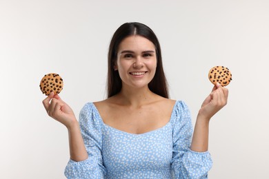Young woman with chocolate chip cookies on white background