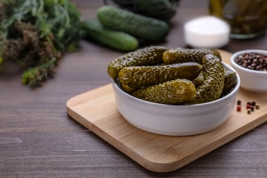 Photo of Bowl of pickled cucumbers and ingredients on wooden table