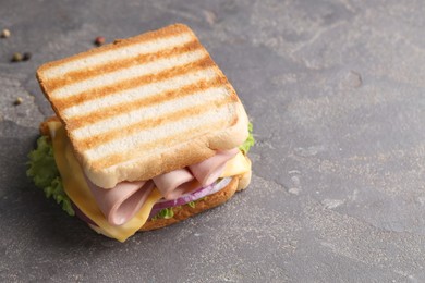 Photo of Delicious sandwich with boiled sausage, cheese and onion on grey textured table, closeup. Space for text