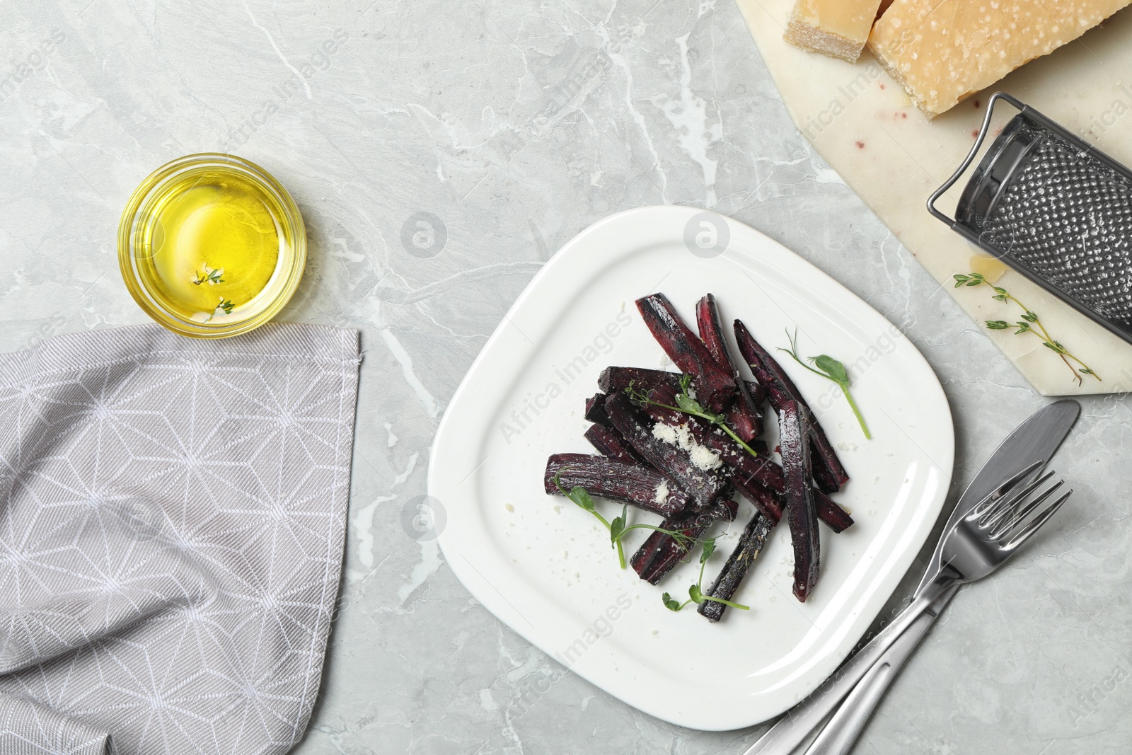 Photo of Tasty baked black carrot served on light grey marble table, flat lay