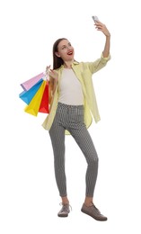 Stylish young woman with shopping bags taking selfie white background