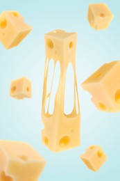 Pieces of cheese falling on light blue background