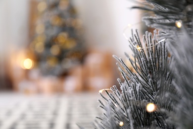 Photo of Beautiful Christmas tree decorated with fairy lights in stylish room interior, closeup. Space for text