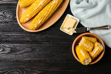 Photo of Flat lay composition of boiled corn cobs on black wooden table. Space for text