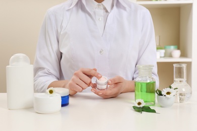 Photo of Female dermatologist testing skin care product at table, closeup