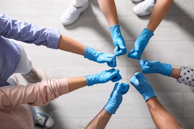 Photo of Group of people in blue medical gloves showing thumbs up indoors, top view