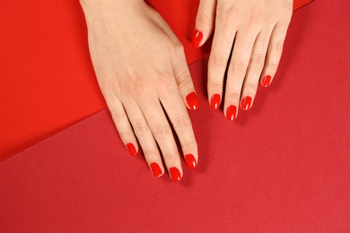 Photo of Woman showing manicured hands with red nail polish on color background, top view