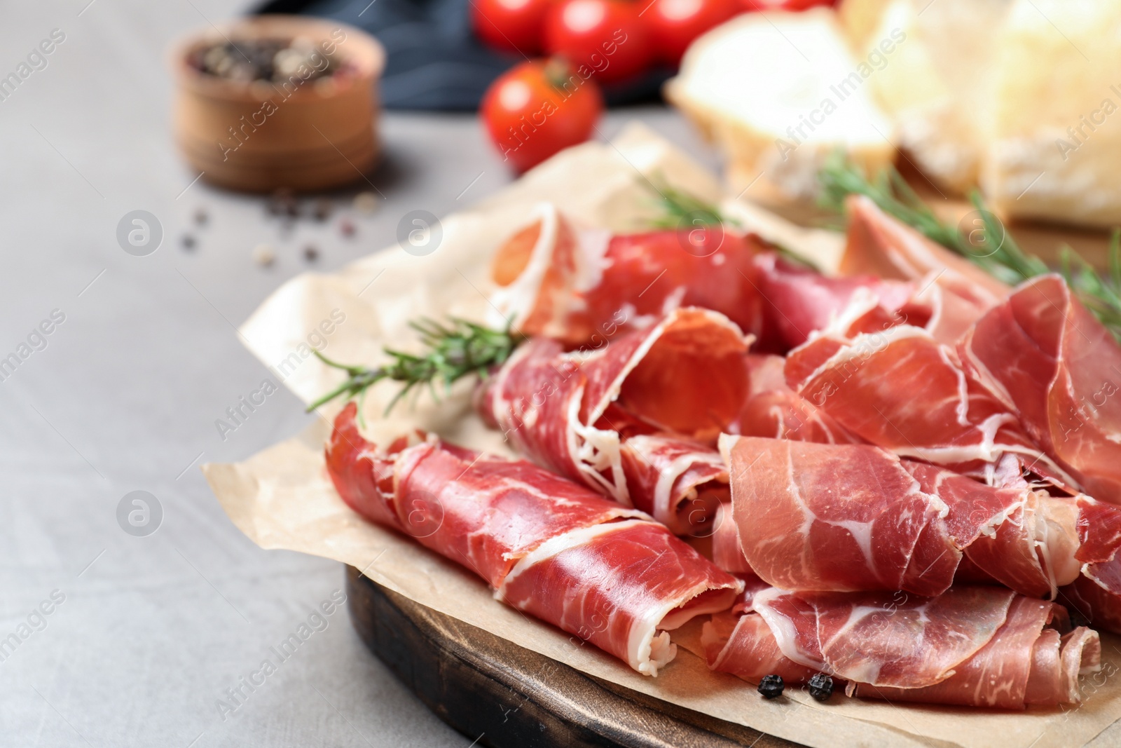 Photo of Slices of tasty prosciutto on grey table, closeup