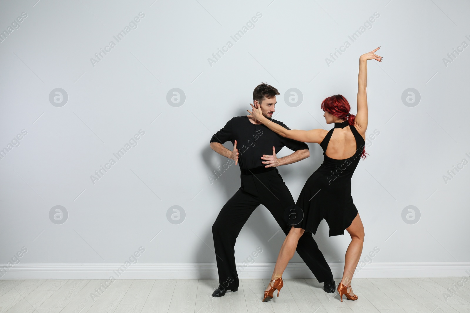 Photo of Beautiful young couple dancing near light wall. Space for text