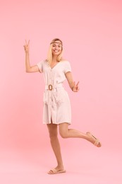 Photo of Beautiful hippie woman showing peace signs on pink background