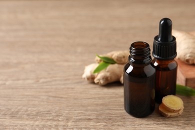 Photo of Ginger essential oil in bottles on wooden table. Space for text