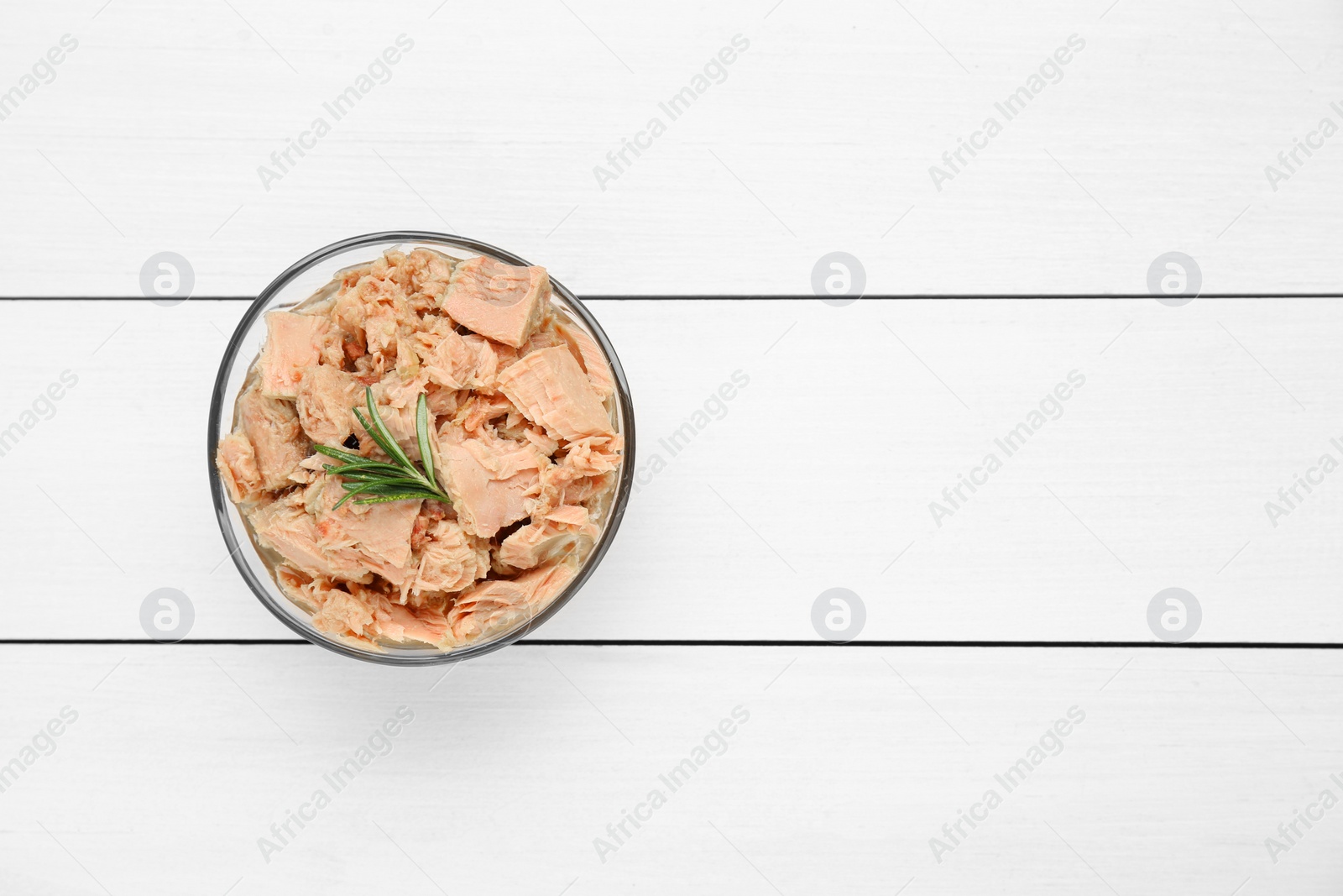 Photo of Bowl with canned tuna and rosemary on white wooden table, top view. Space for text
