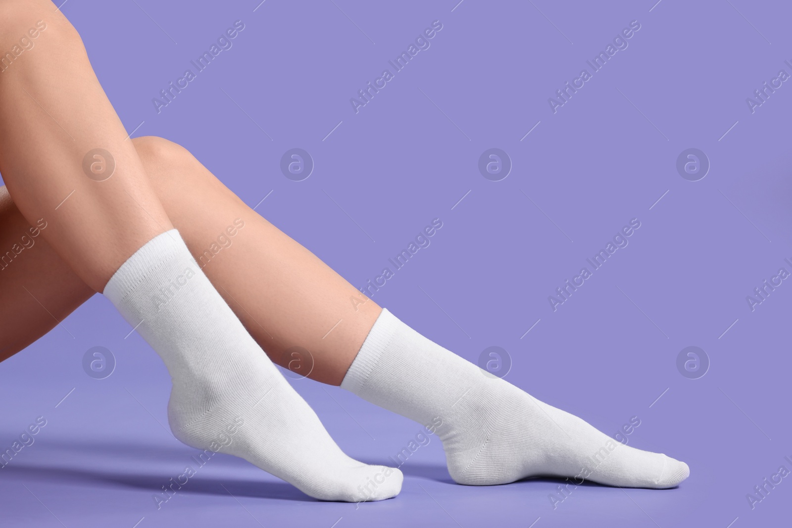 Photo of Woman in stylish white socks on violet background, closeup