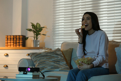 Young woman watching movie using video projector at home