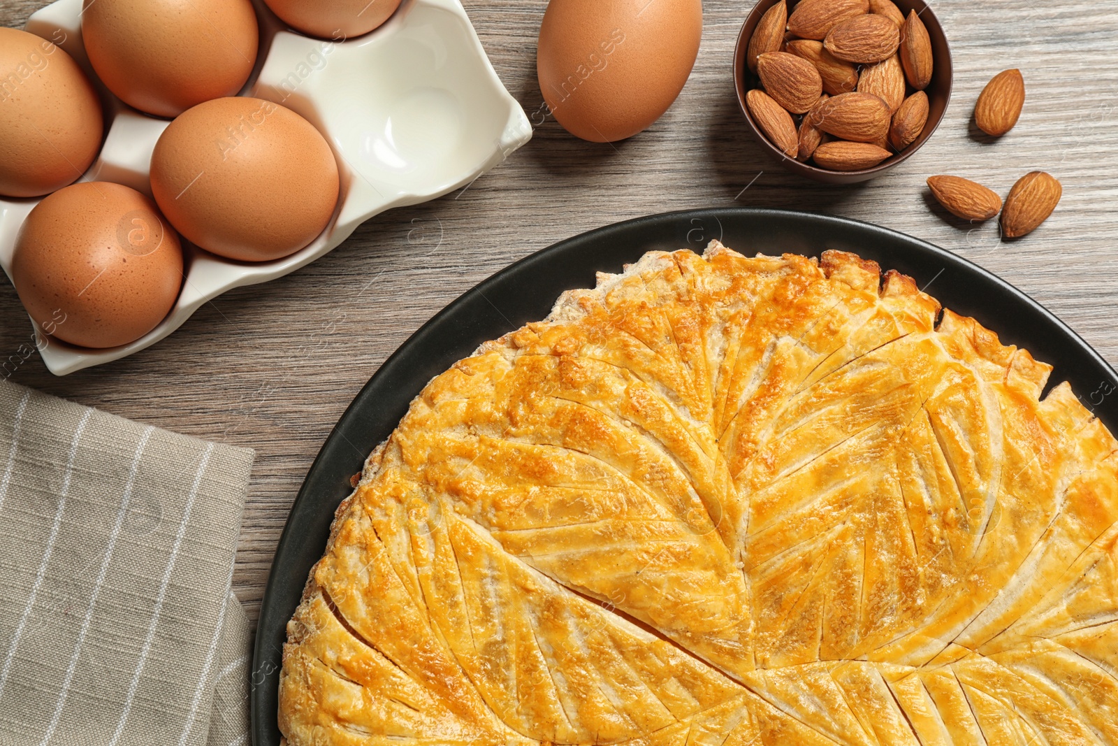 Photo of Traditional galette des rois and ingredients on wooden table, flat lay