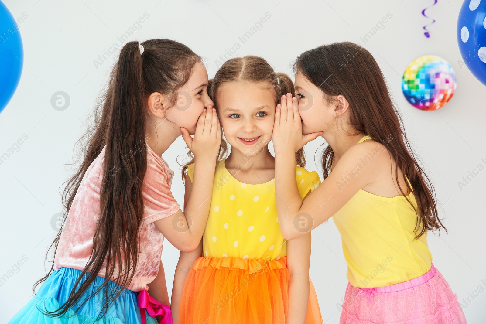 Photo of Adorable little girls and decor for birthday party on light background