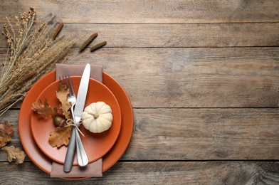 Photo of Festive table setting with autumn decor on wooden background, flat lay. Space for text