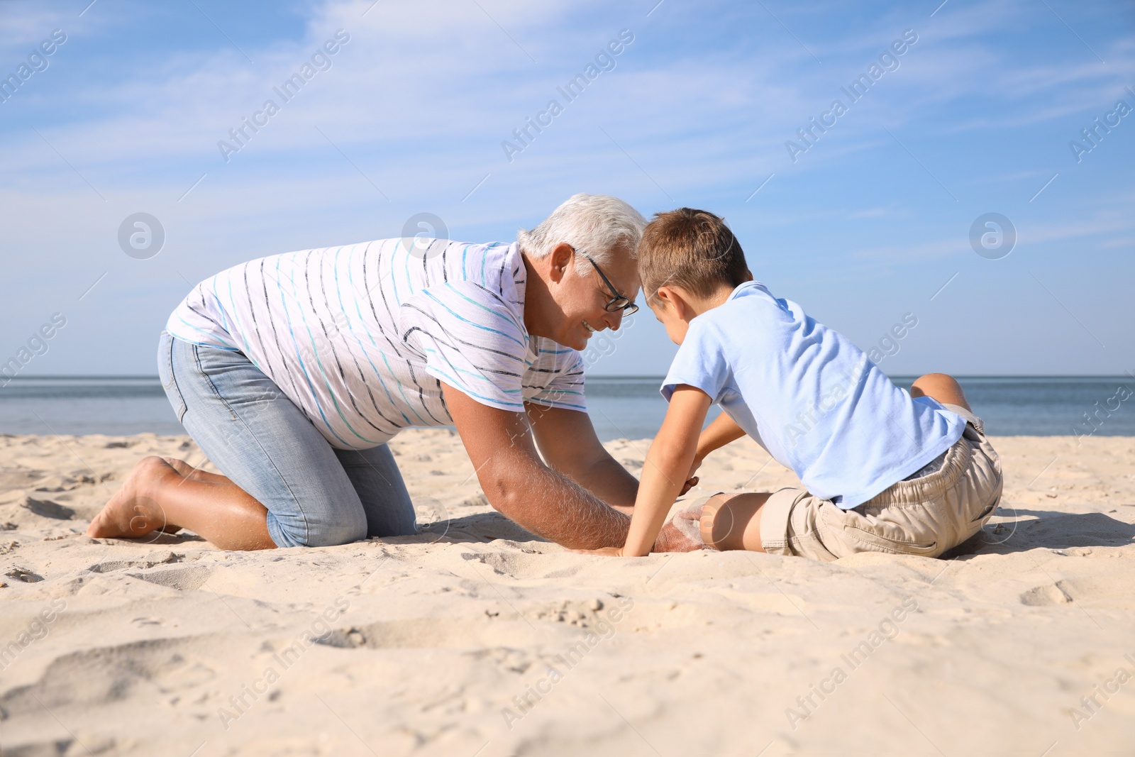 Photo of Cute little boy with grandfather spending time together on sea beach