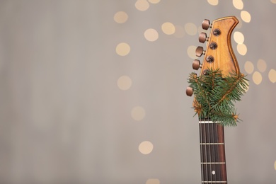 Photo of Guitar with fir tree twig against blurred lights, space for text. Christmas music