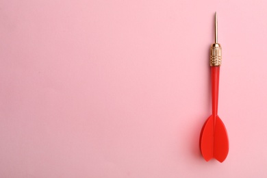 Photo of Red dart arrow on pink background, top view with space for text