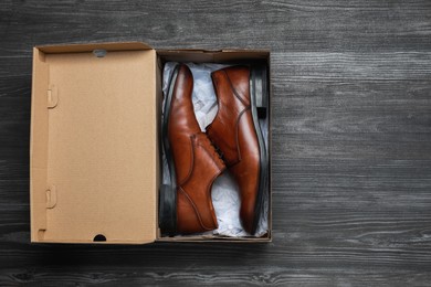 Photo of Stylish men's shoes in cardboard box on wooden floor, top view. Space for text