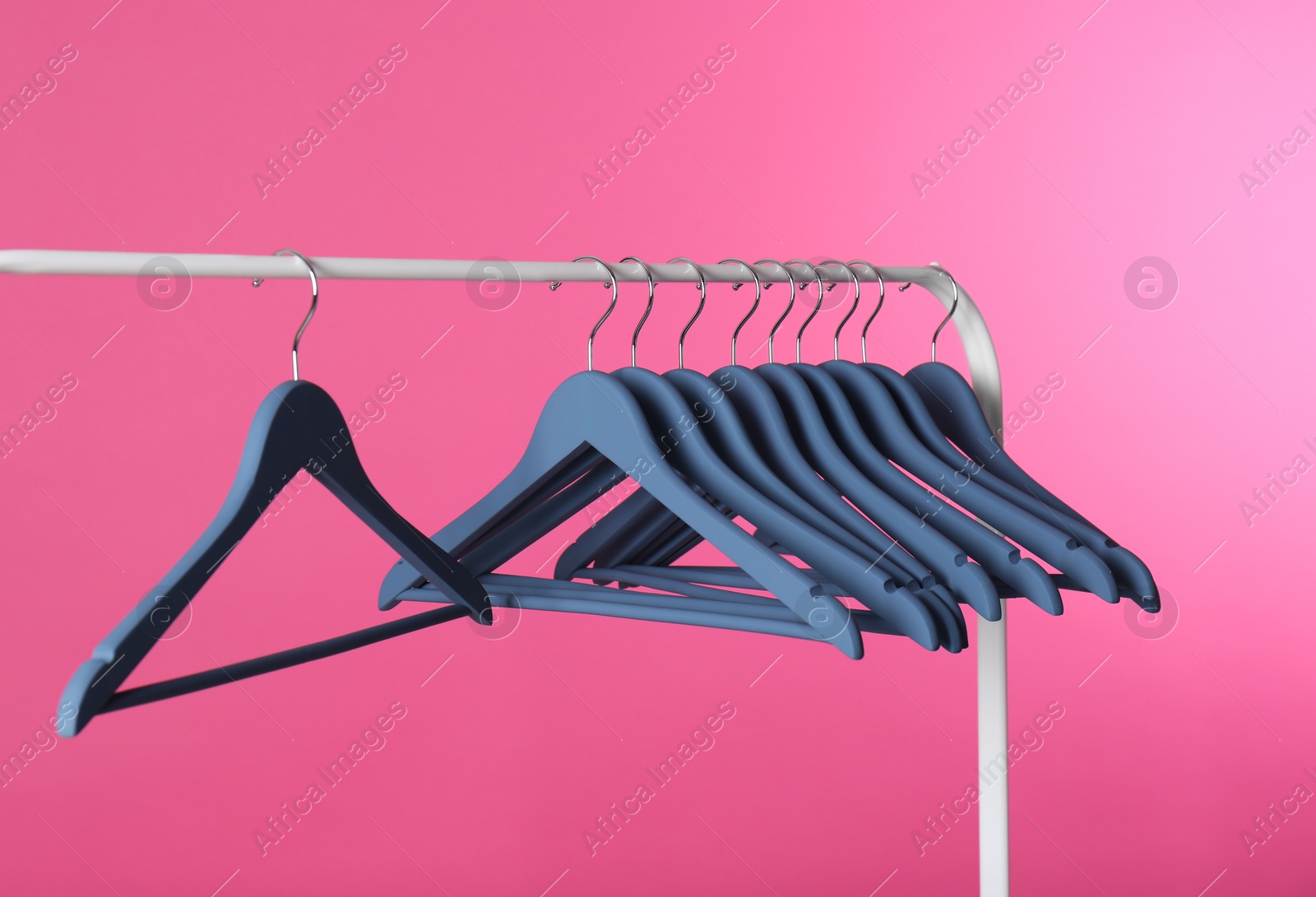 Photo of Metal rack with clothes hangers on color background