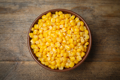 Photo of Delicious canned corn in bowl on wooden table, top view